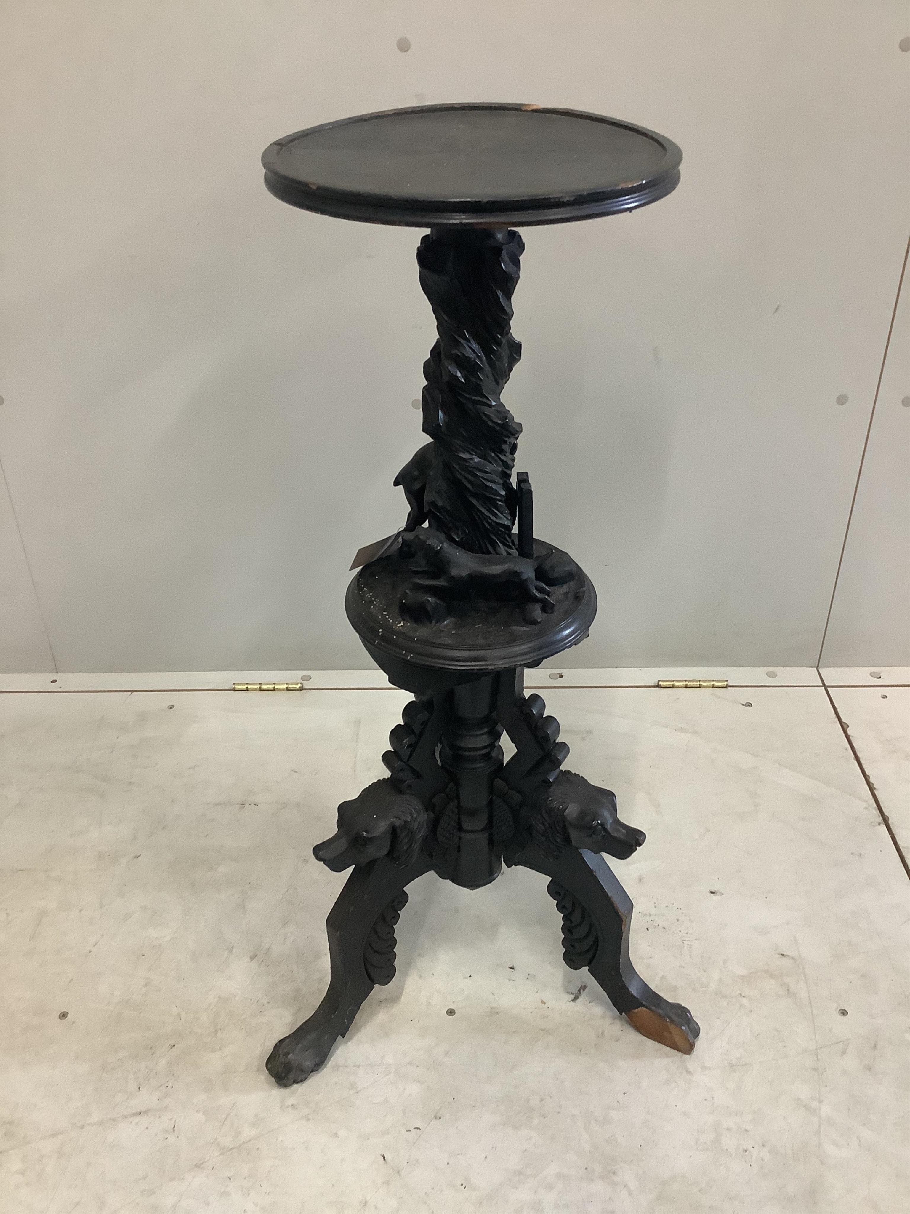 A late 19th century Black Forest ebonised wood urn stand carved with a running deer and hounds heads, height 90cm. Condition - poor, numerous losses